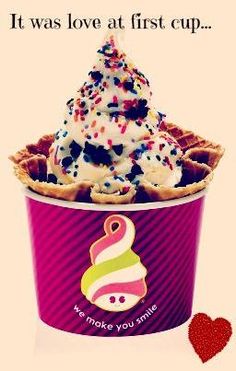 an ice cream sundae with sprinkles in a pink cup next to a red heart