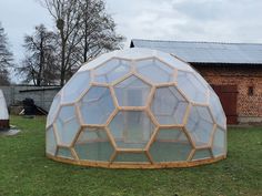 a large glass dome sitting on top of a lush green field next to a brick building