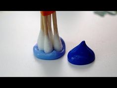 two toothbrushes sticking out of a blue cup next to a drop of water