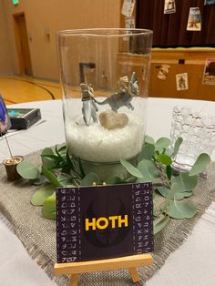 a table topped with a glass vase filled with water and small figurines on top of it