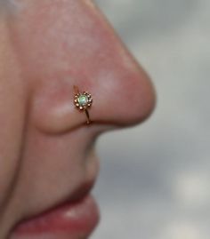 a woman's nose with an opal in the middle and a gold nose ring on it