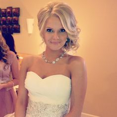 a woman in a strapless white dress posing for a photo with her wedding jewelry