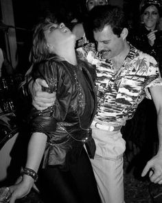 black and white photograph of two people dancing at a party with other people in the background