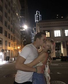 a man and woman standing next to each other in front of a building at night