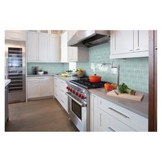 a kitchen with white cabinets and green tile backsplash, stainless steel appliances and an oven