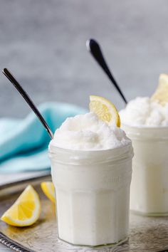 two small jars filled with whipped cream and lemon wedges on a silver platter