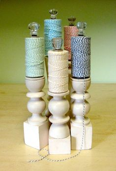 four spools of thread sitting on top of each other in front of a wooden stand