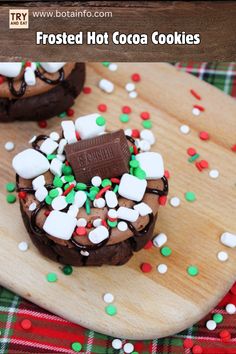 chocolate frosted hot cocoa cookies with marshmallows on a wooden cutting board