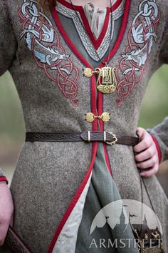 a woman dressed in medieval clothing and holding a horse bridle on her shoulder