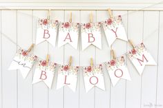 a baby shower banner hanging on a clothes line with flowers and the words, baby bloom