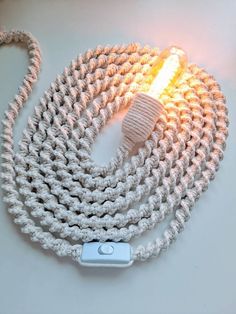 a white cord with a light on it sitting on top of a table next to a cell phone