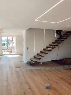 an empty room with stairs and hard wood flooring