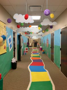 an office hallway decorated in rainbow colors with clouds and balls hanging from the ceiling above