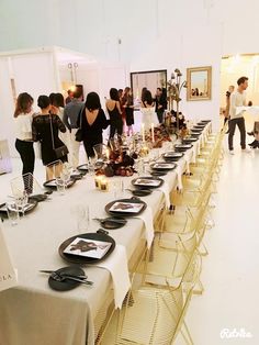 a group of people standing around a long table with plates and wine glasses on it