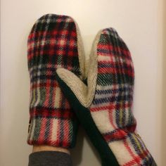 a pair of plaid mittens sitting on top of a white wall