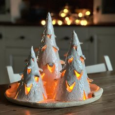 three lit up christmas trees sitting on top of a wooden table