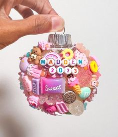 a hand holding a glass ornament with various items on it