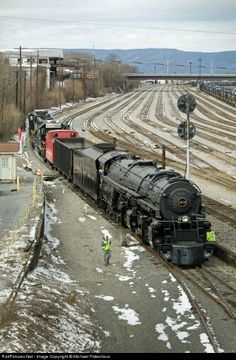 a train traveling down tracks next to snow covered ground