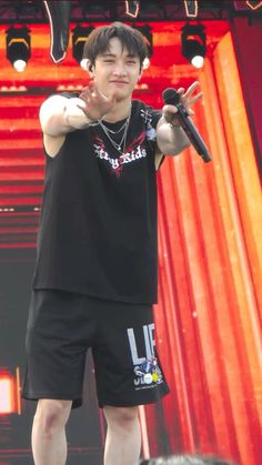 a young man standing on top of a stage holding a microphone in his right hand