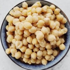 a blue bowl filled with chickpeas on top of a white marble countertop