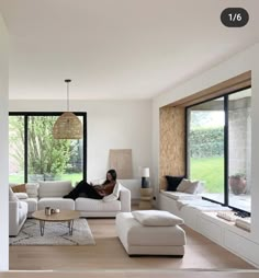 a person laying on top of a couch in a living room next to large windows