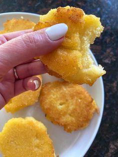 a person is holding up some food on a white plate with yellow crumbs