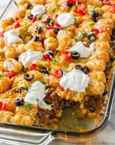 a casserole dish filled with meat, cheese and olives on a table