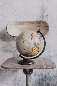 an old wooden chair with a globe on it