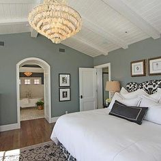 a bedroom with a chandelier hanging from the ceiling and a bed in front of it