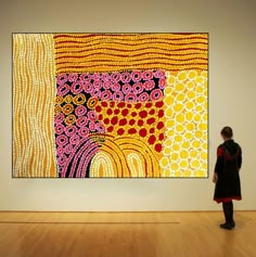 a woman standing in front of a large painting on display at an art gallery,