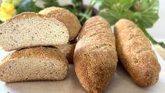 four loaves of bread sitting next to each other on a table with flowers in the background