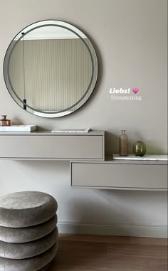 a round mirror sitting on top of a white counter next to a stool and table