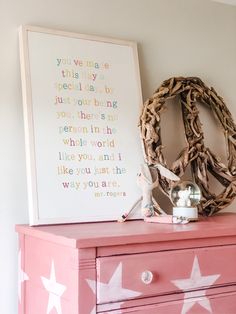 a pink dresser with white stars on it and a peace sign above the top shelf