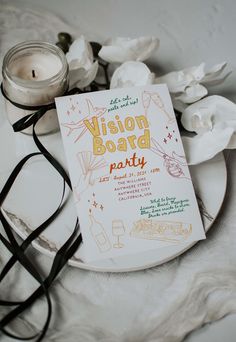 a book sitting on top of a white plate next to a candle and some flowers