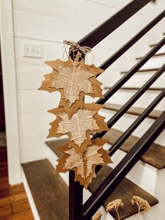 some leaves are hanging on the handrail in front of a stair case with wood flooring