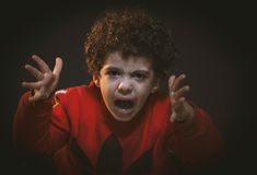 a young boy with his hands in the air and making an angry face while wearing a red shirt