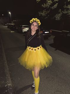 a woman in a yellow tutu and sunflower headband walking down the street