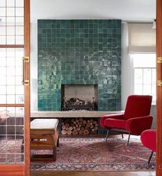 a living room with red chairs and a fireplace