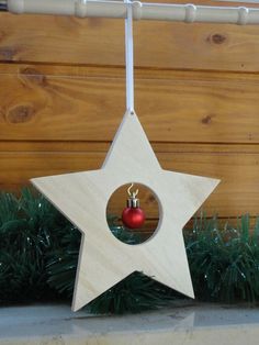 a wooden star ornament with a red ball hanging from it