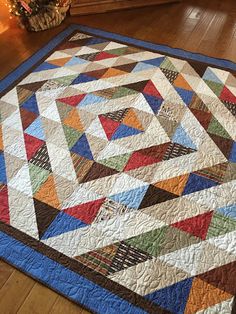 a colorful quilt is on the floor next to a christmas tree