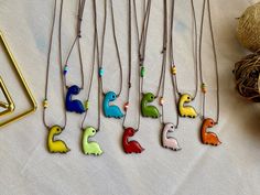 several necklaces with different colored birds on them next to some yarn and other items