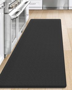 a kitchen with white cabinets and stainless steel appliances in the background, along with a black mat on the floor