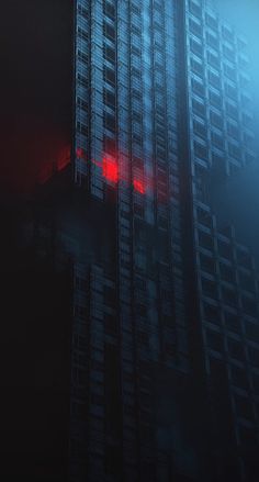 a tall building with a red traffic light on it's side in the fog