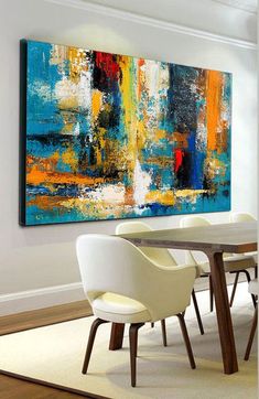 an abstract painting hangs above a dining room table