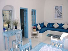 a living room filled with blue furniture and white walls on either side of the couch