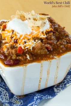 chili concoction with sour cream on top, served in a white and blue dish