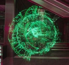 a large green circular object in the middle of a room with stairs and lights on it