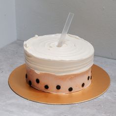 a cake with white frosting and black polka dots on the bottom is sitting on a gold plate