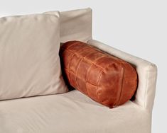 a brown leather pillow sitting on top of a white couch