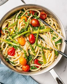 a pan filled with pasta, tomatoes and asparagus